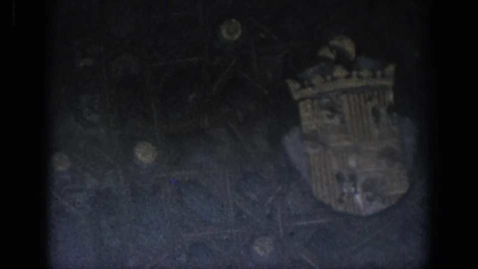 Final 8mm frame showing the crowned shield shifted to the right, with heavy shadow and textured wall detail around it.