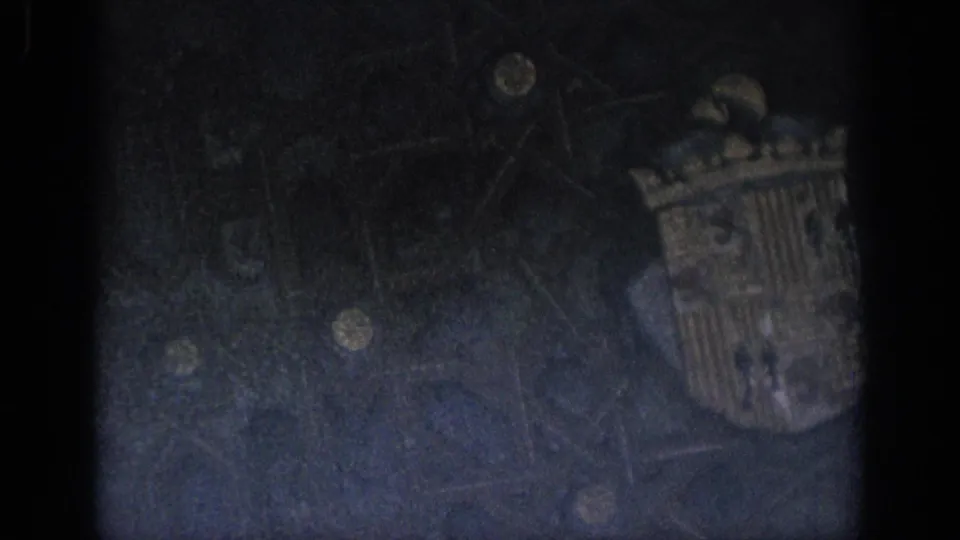 Underexposed 1966 Spain 8mm frame with faint stonework detail, heavy shadowing, grain, and dark film borders.