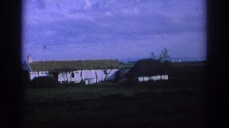 1966 Spain rural roadside view with a white farmhouse, low outbuilding, trees and fields framed by a car window.