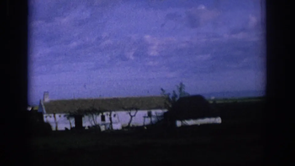 1966 Spain 8mm still showing rural farm structures partly obscured by the moving car window edge.