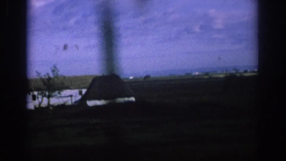 Final 1966 Spain frame shows the farm receding behind a car-window pillar, with fields and sky in soft 8mm color.