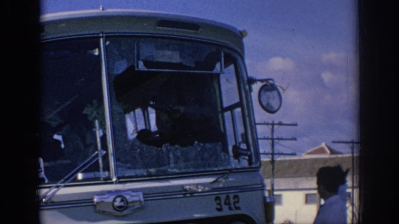 1966 Spain frame of a bus with shattered windshield glass, bus number 342, and a nearby pedestrian in profile.