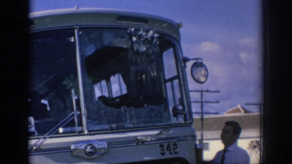 1966 Spain 8mm frame showing a passenger bus numbered 342 with shattered windshield glass and men inspecting the front area.