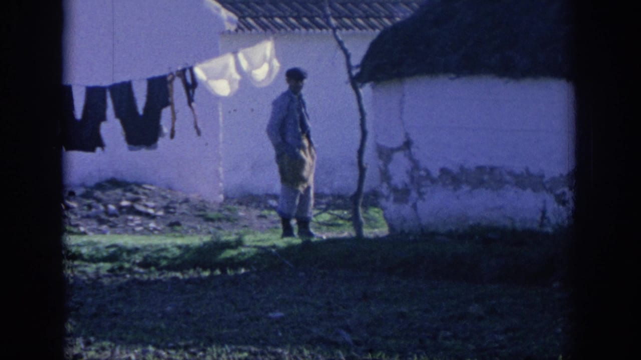 Man standing beside a whitewashed rural building with laundry hanging nearby.