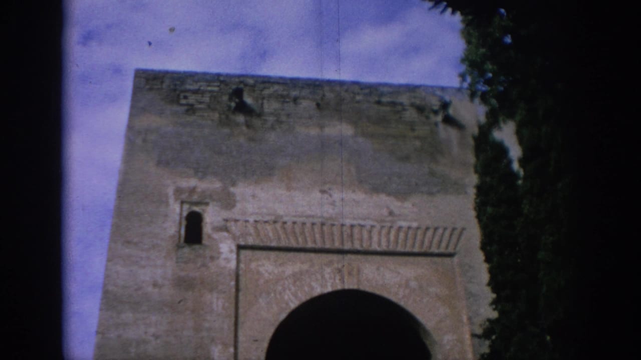 Upper section of a stone gateway with a large arched opening and dark tree edges.