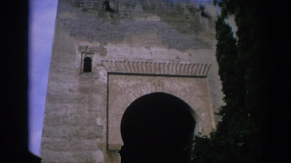 1966 Spain 8mm frame showing the lower view of a stone gateway, with a large dark arch and decorative masonry above it.