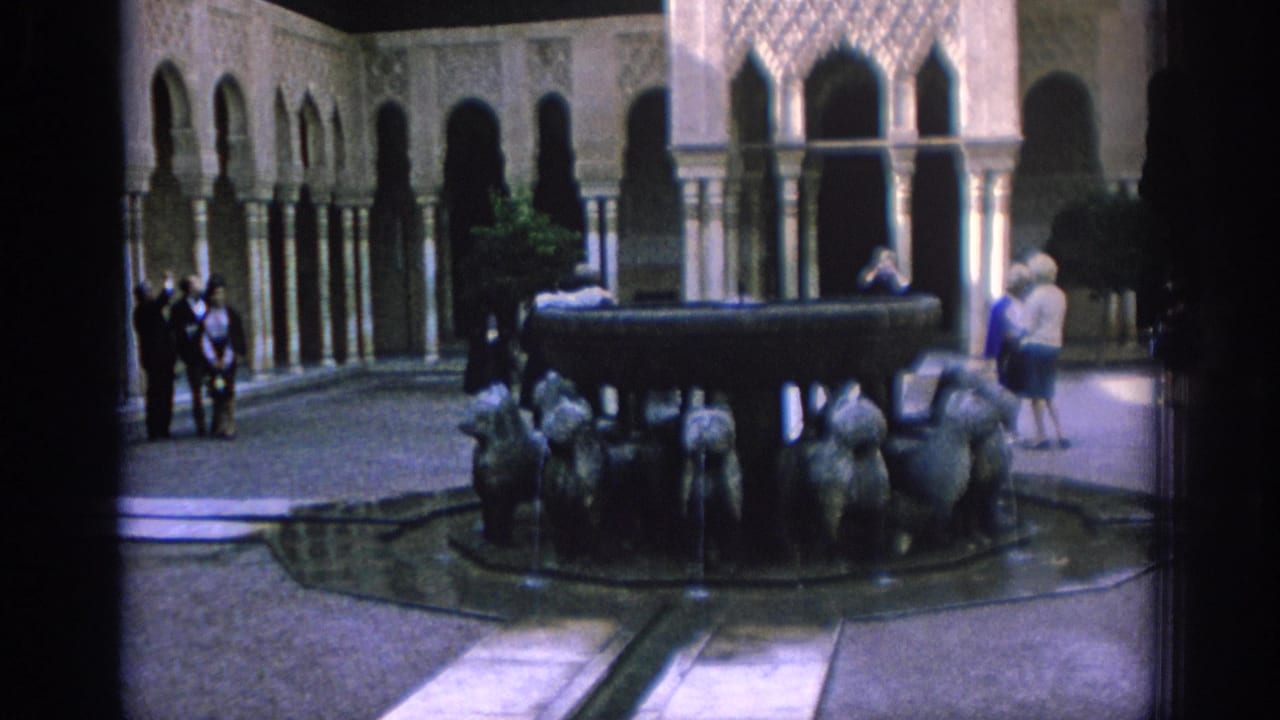 1966 Spain home-movie frame showing a Moorish-style courtyard with arched colonnades, a central sculptural fountain, and visitors.
