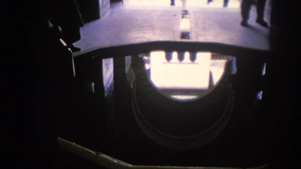 A handheld 1966 Spain view through dark decorative framing toward a bright architectural space, with partial visitor figures visible.