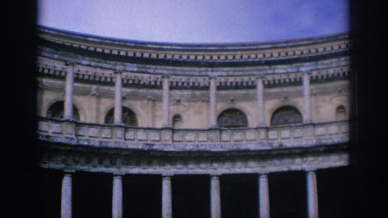 1966 Spain 8mm frame of a circular or curved historic facade with arched windows, balcony rail, columns, and visible film-edge shadow.