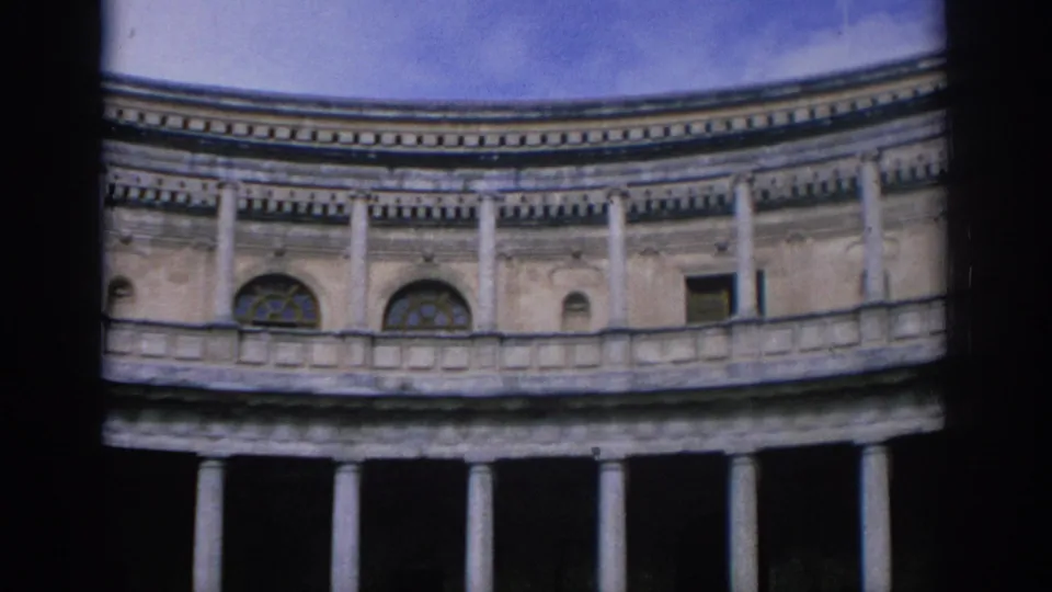 1966 Spain 8mm frame showing a curved classical stone building with columns and arched windows, partly obscured by dark film edges.
