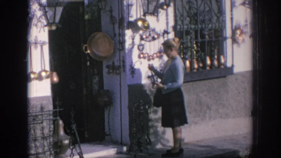 A woman browses copper-colored decorations and cookware outside a Spanish shop in 1966.