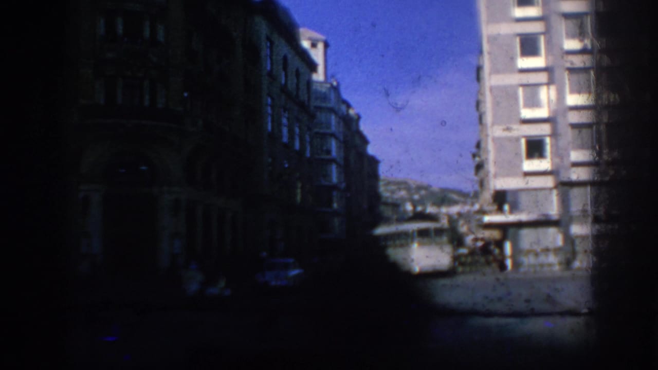 Dark street view with bus and apartment building partly obscured by frame edge.