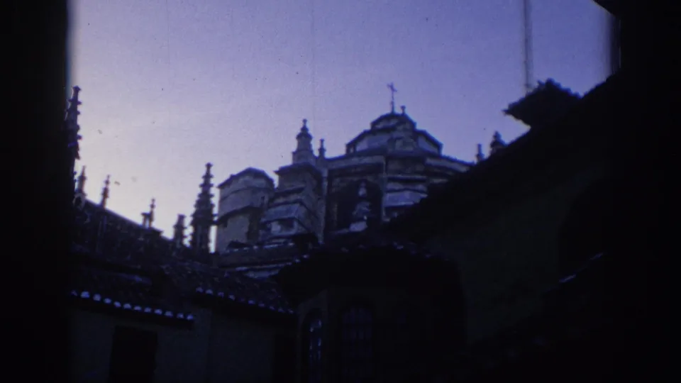 1966 Spain travel frame showing a cathedral exterior with spires, domes, rooflines, and deep shadow in the foreground.