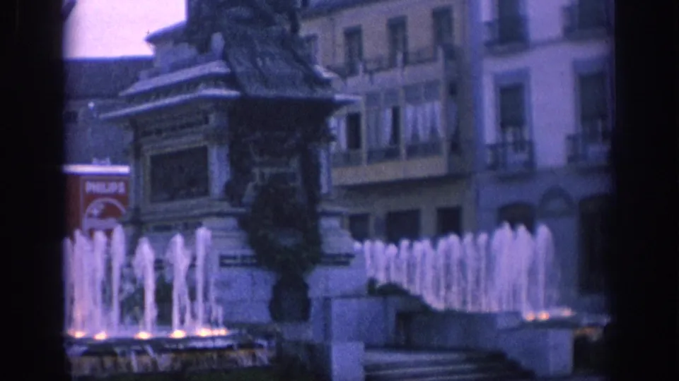 1966 Spain 8mm frame with a statue fountain, surrounding plaza buildings, balconies, and a partly visible Philips advertisement.