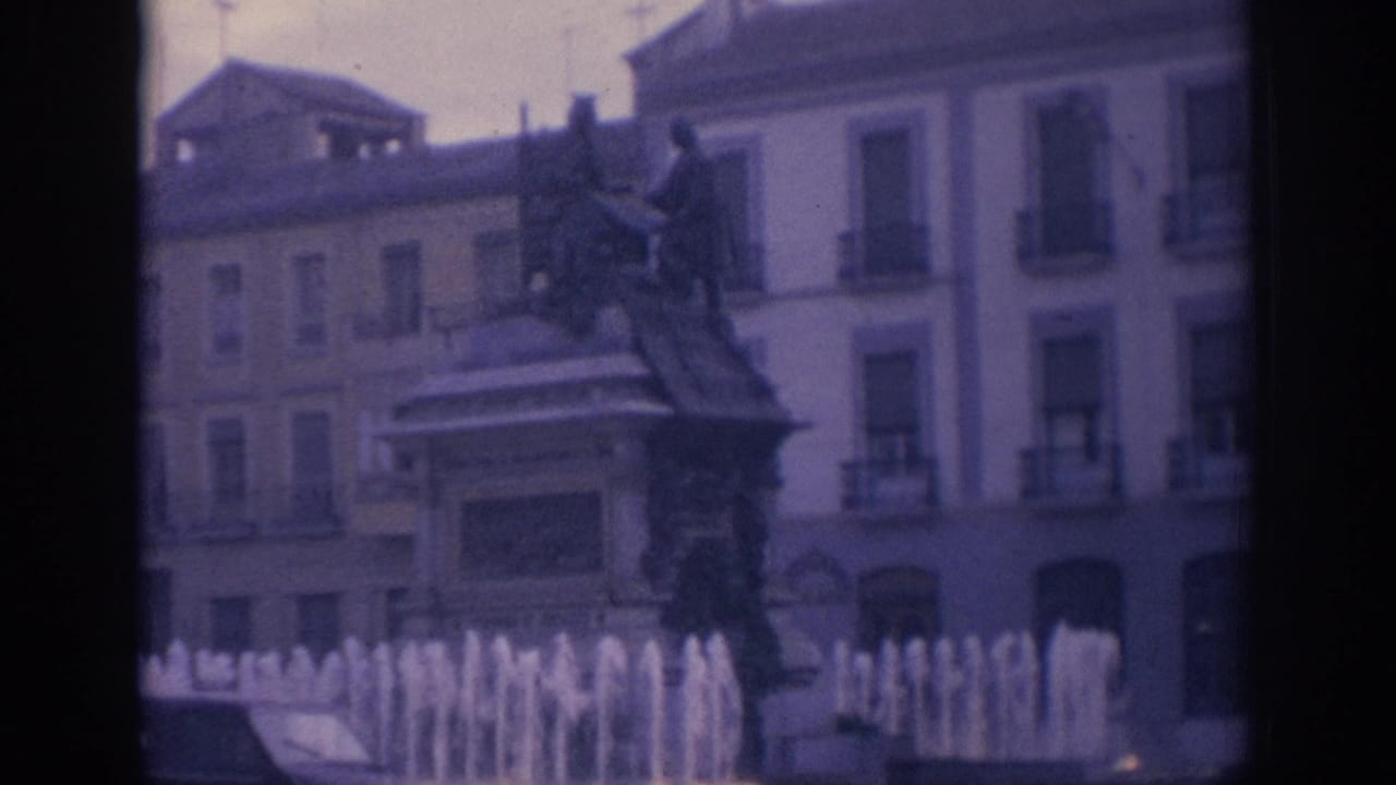 Public fountain and statue in front of pale urban buildings.