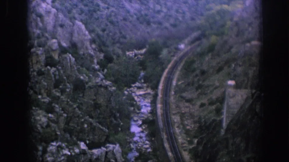 Spain 1966 home-movie view of a curving railway line running beside a narrow rocky stream through steep terrain.