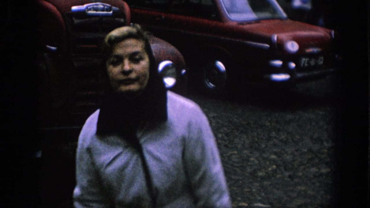 A close 1966 Spain street view shows a woman in a light coat and dark headscarf with classic red cars behind her.