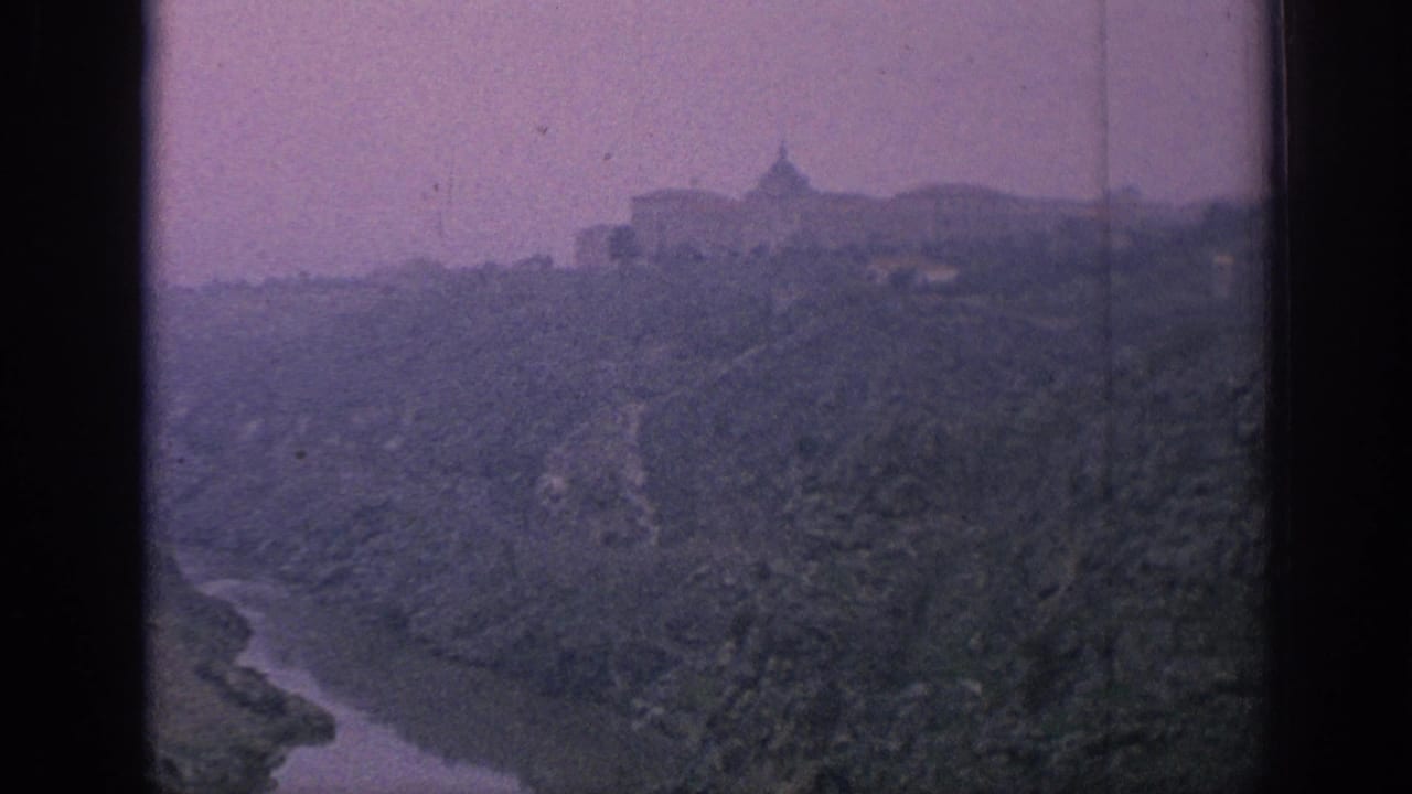 1966 Spain home-movie view of a mountain village or ridge-top town above a winding river valley, with faded color and soft focus.