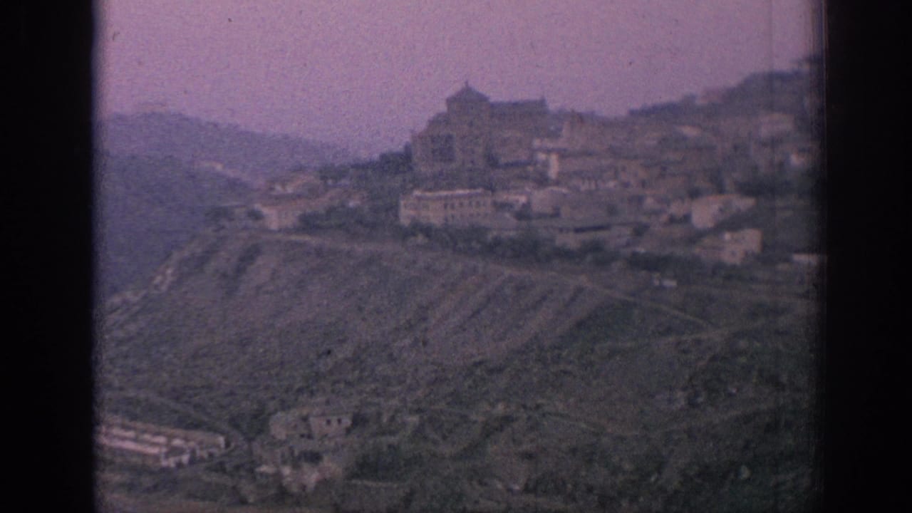 Hilltop town with a prominent building and clustered houses on a sloping ridge.