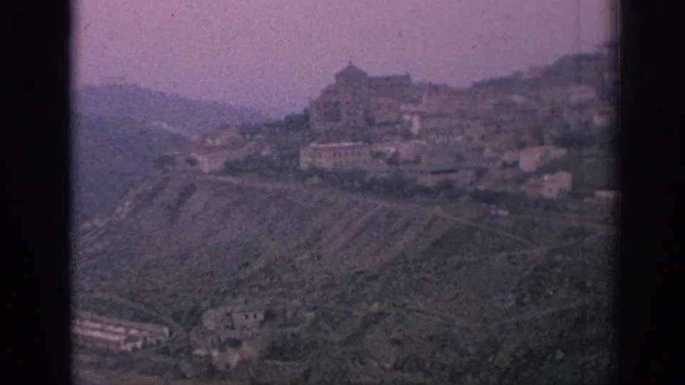 1966 Spain travel footage frames a hillside town with clustered buildings and a prominent structure on the ridge.