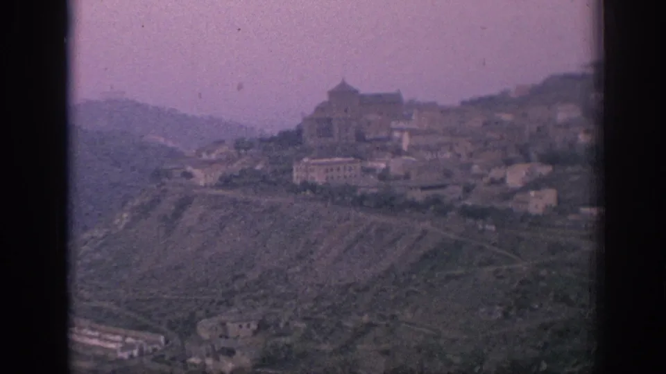 A 1966 Spain home-movie shot shows a hillside settlement, terraced slopes, and valley below in faded 8mm color.