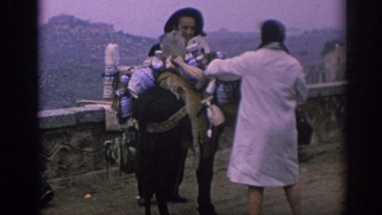 Woman reaches toward goods on a donkey while the bearded handler stands nearby.