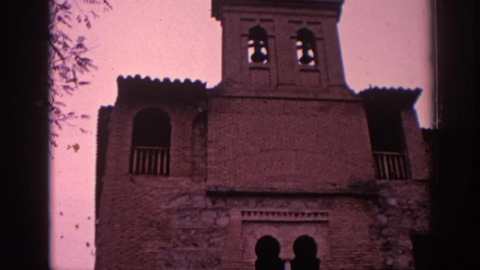 1966 Spain home-movie frame showing the museum's upper facade with a bell tower, arched balcony opening, and crenellated roofline.