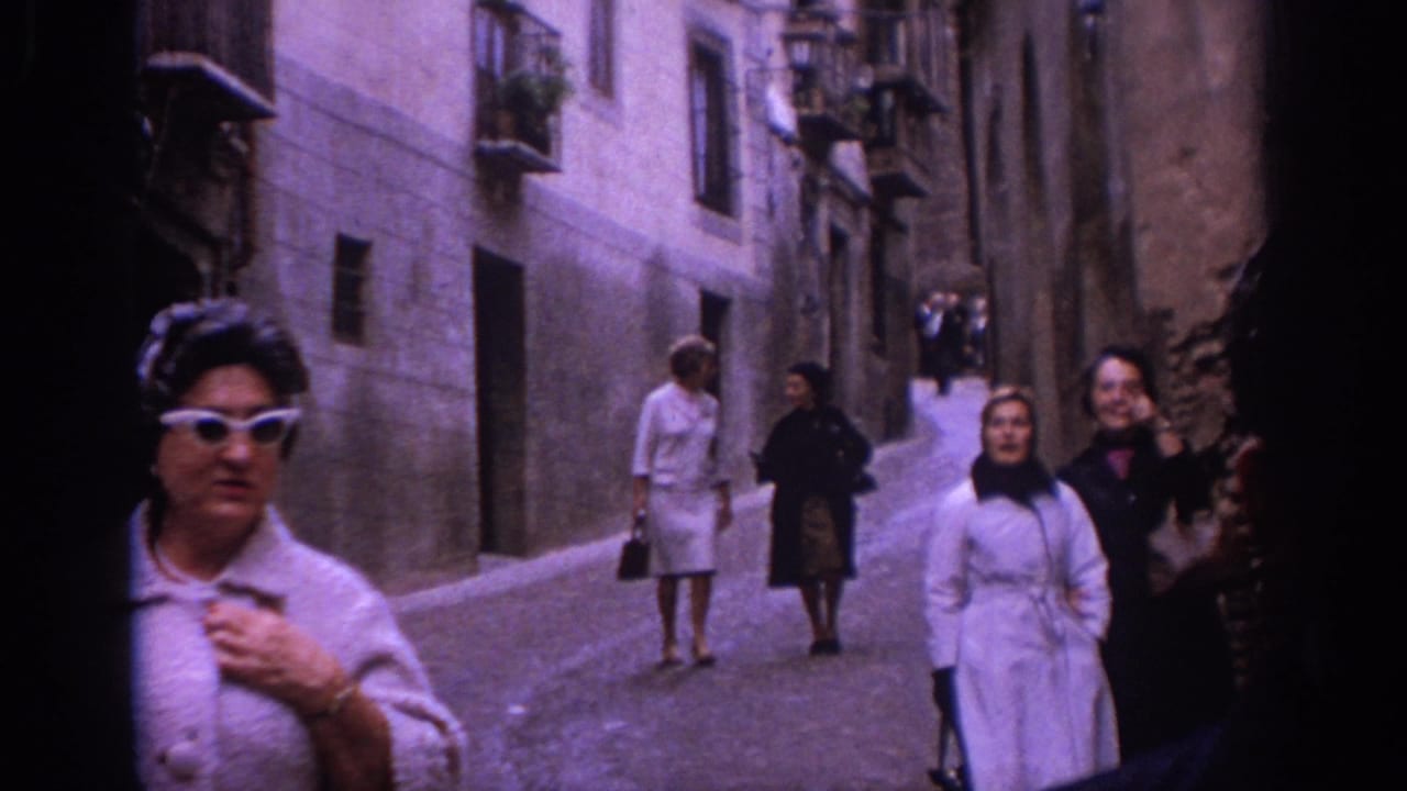 Woman in cat-eye sunglasses passes near the camera as others walk behind her.