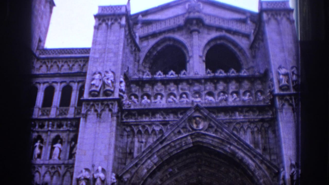 1966 Spain 8mm frame of a Gothic cathedral entrance with carved figures, arched openings, and dense stone ornament.