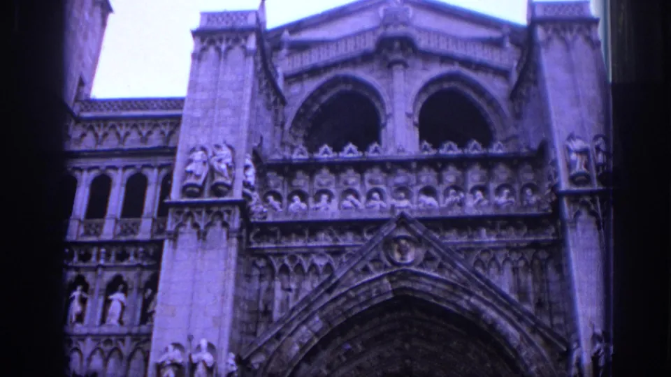 1966 Spain 8mm frame of a Gothic cathedral entrance with carved figures, arched openings, and dense stone ornament.