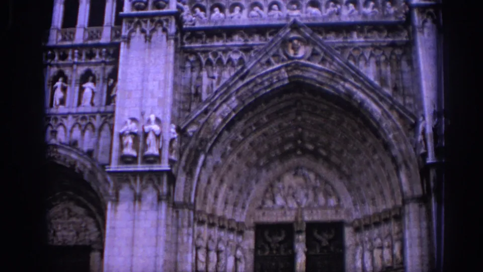 1966 Spain 8mm frame showing the cathedral entrance with a large pointed arch, rows of carvings, and dark doors below.