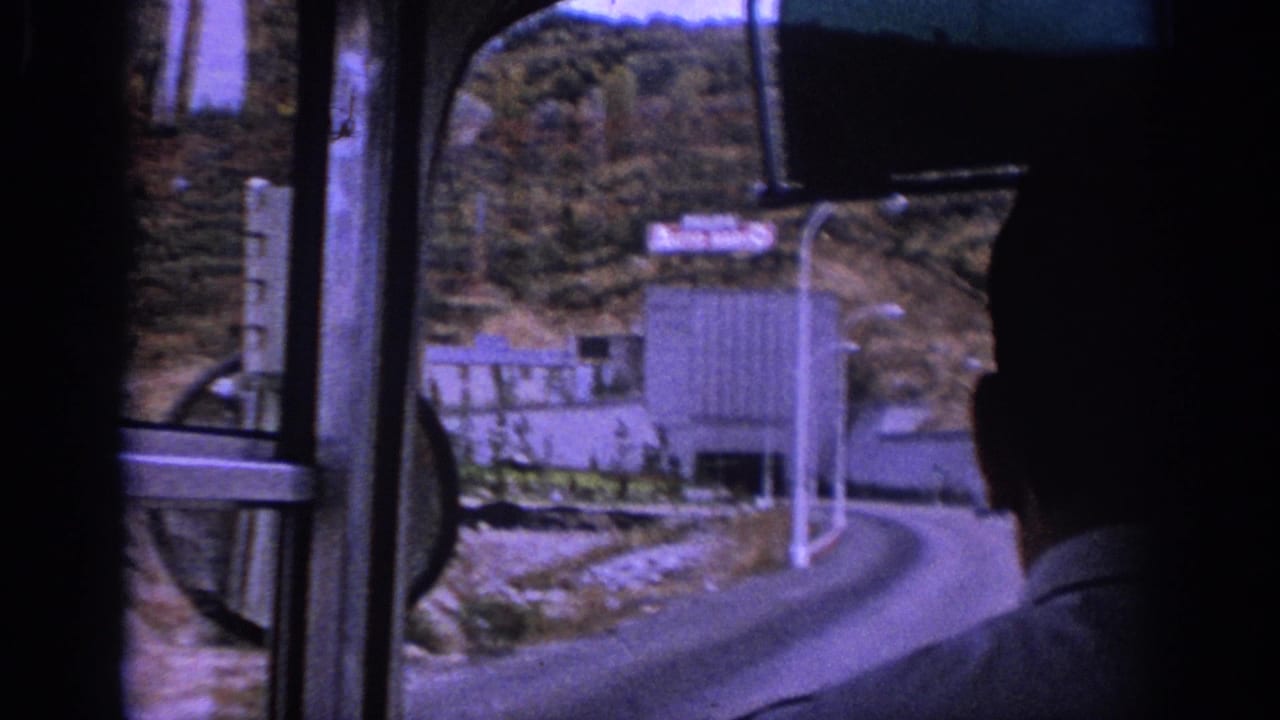 Bus passenger view toward a road curving into a tunnel entrance.