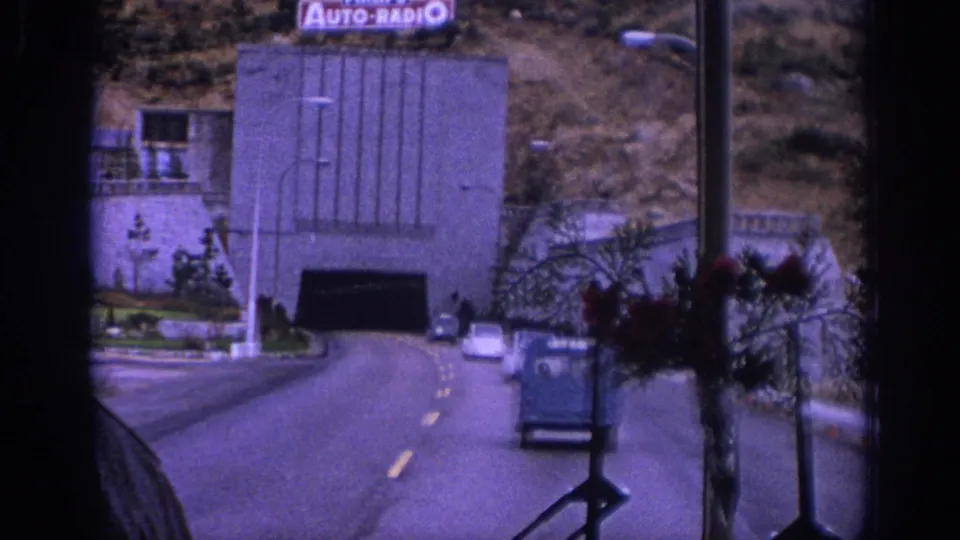 1966 Spain bus POV of cars ahead on a two-lane road approaching a tunnel entrance with an Auto-Radio sign above.