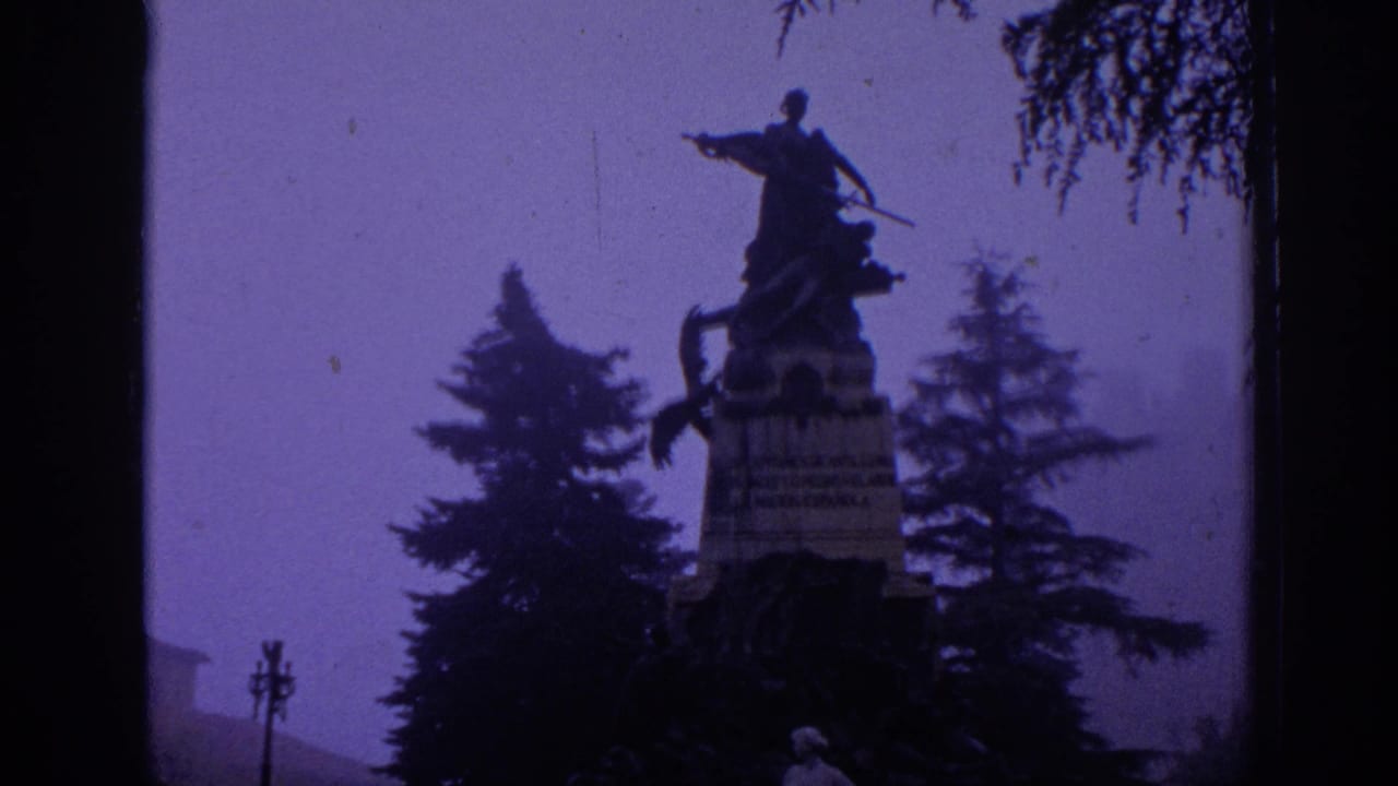 1966 Spain 8mm frame showing a dark equestrian monument above trees, with soft focus and purple color shift.