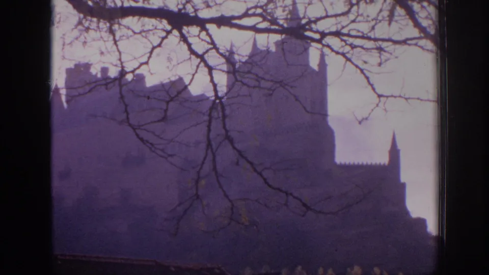 1966 Spain 8mm frame with a broad castle silhouette below leafless branches, seen through a window-like frame edge.