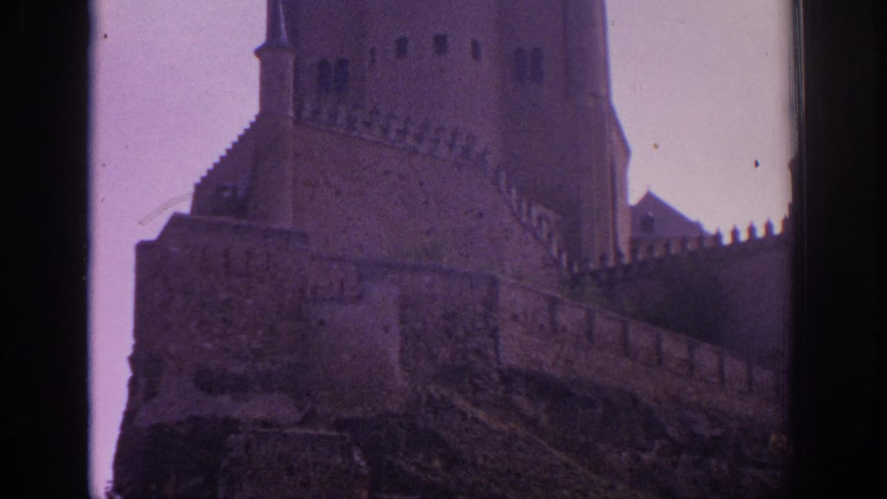 Castle towers and crenellated walls rising above a rocky hillside.