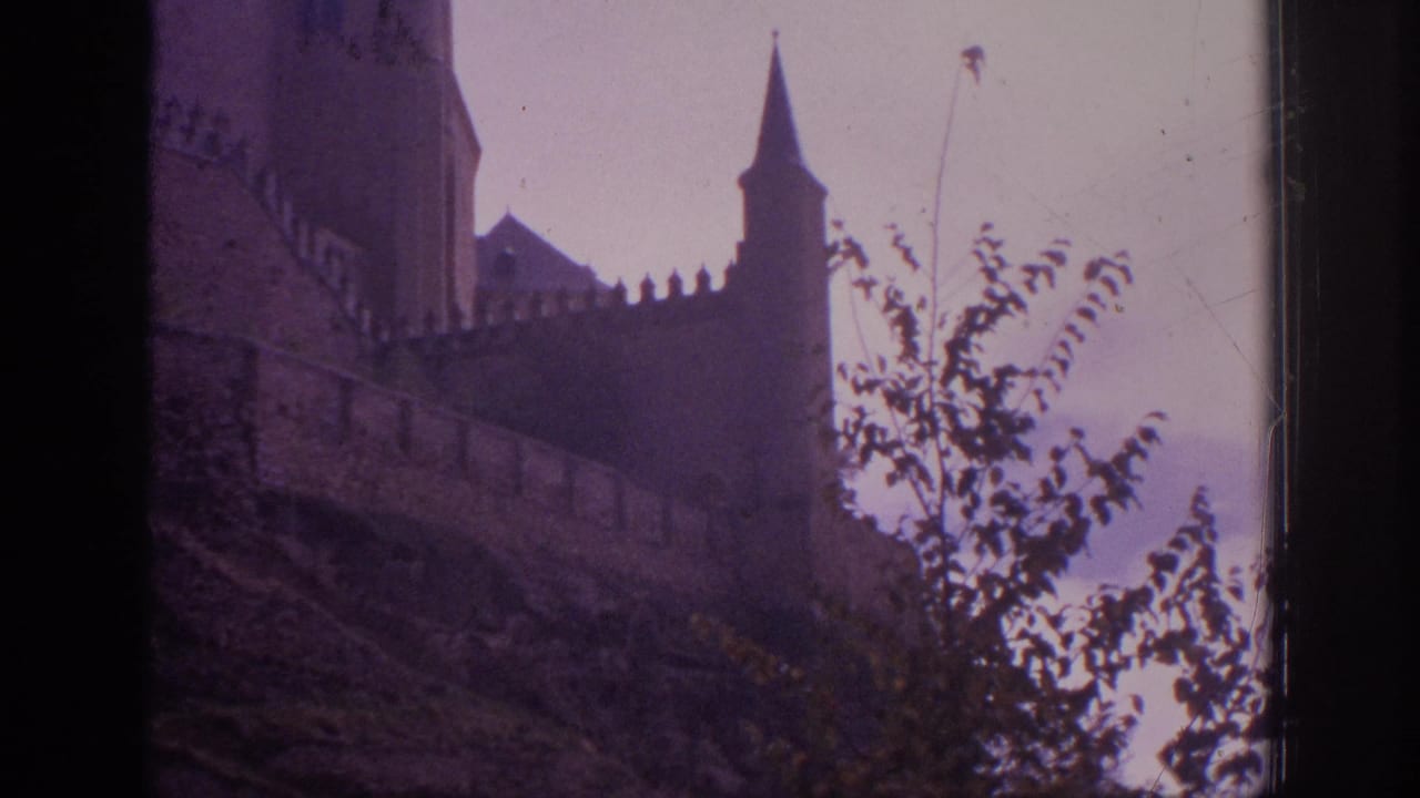 A Spanish castle exterior appears through 8mm film framing, with battlements, a pointed turret, hillside vegetation, and muted color shift.