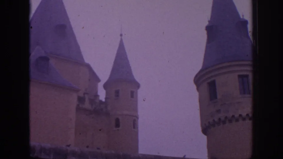 1966 Spain 8mm frame showing several castle towers and rooflines from a close visitor perspective.