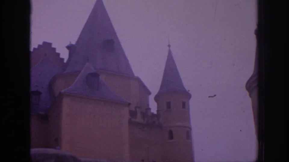 1966 Spain 8mm view of a castle roofline with conical towers, crenellated detail, and muted color from the film scan.