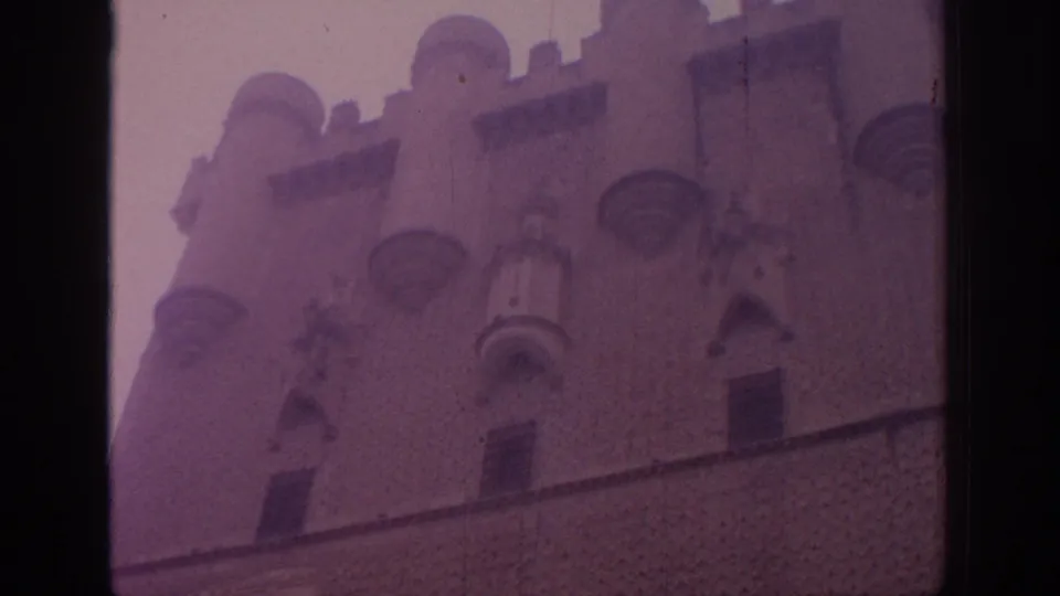 Soft purple 8mm frame of a Spanish castle wall with crenellations, turret details, and dark framing at the bottom.
