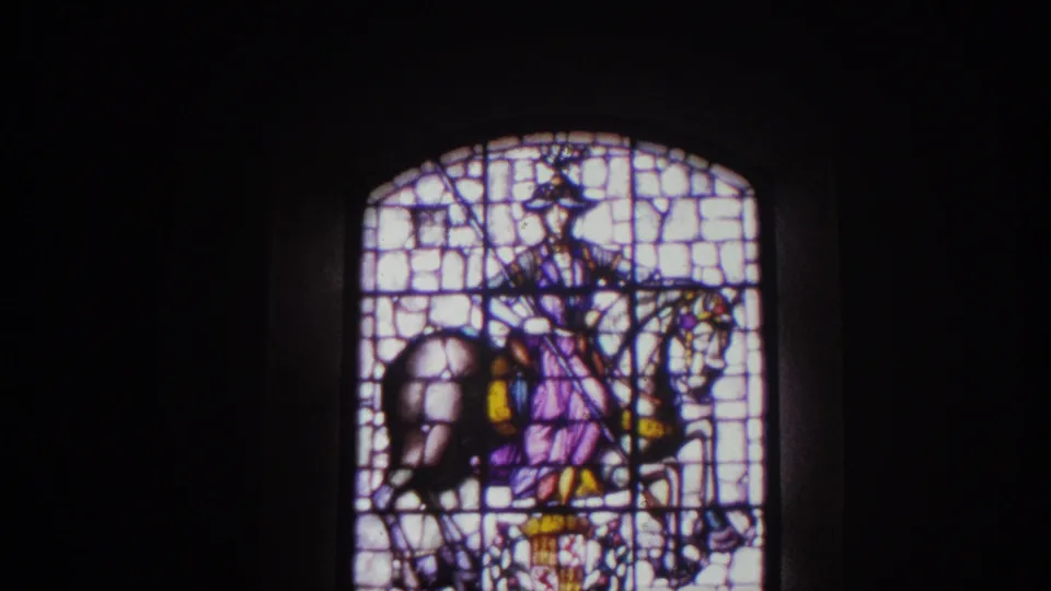 Closer 1966 Spain 8mm view of stained glass depicting a mounted figure, with bright leaded panes against a dark interior.