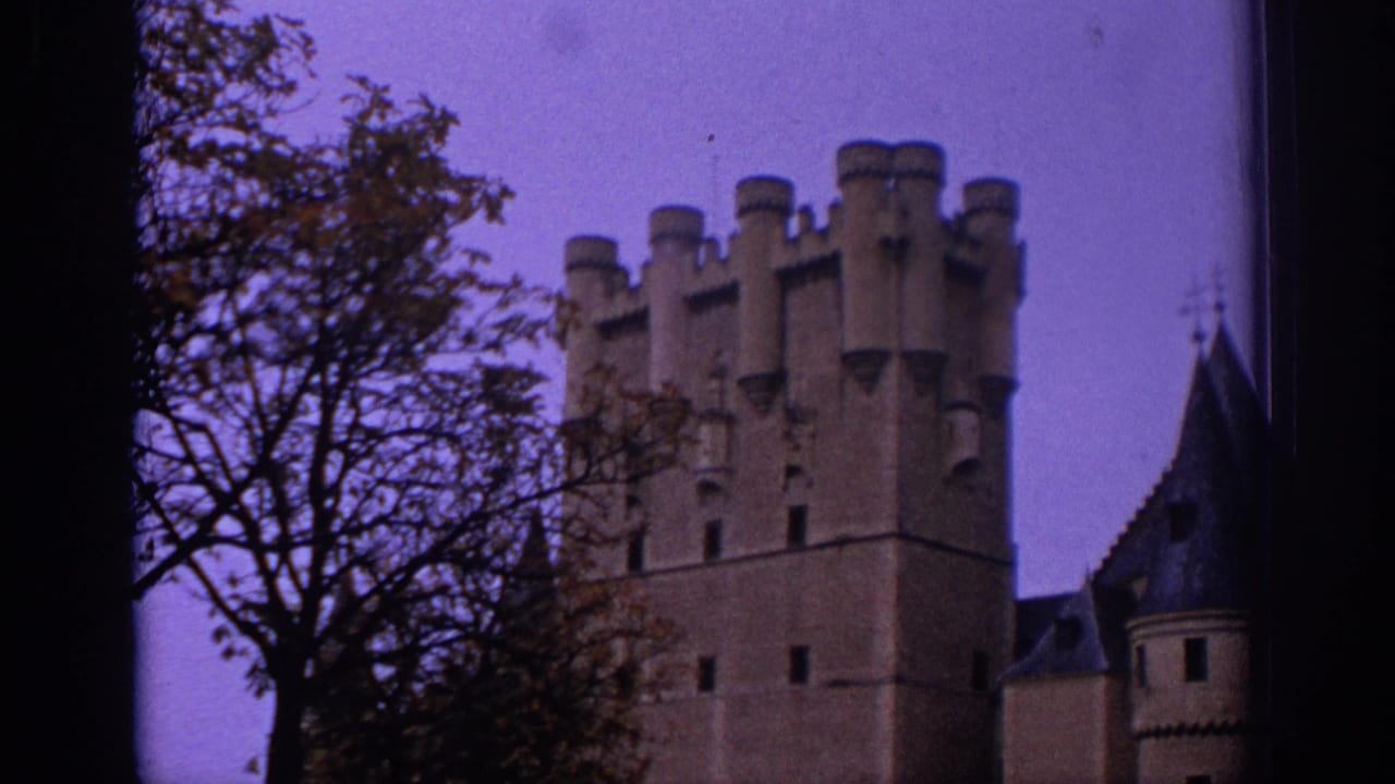 1966 Spain 8mm frame showing a crenellated castle tower partly obscured by trees and dark film edges.