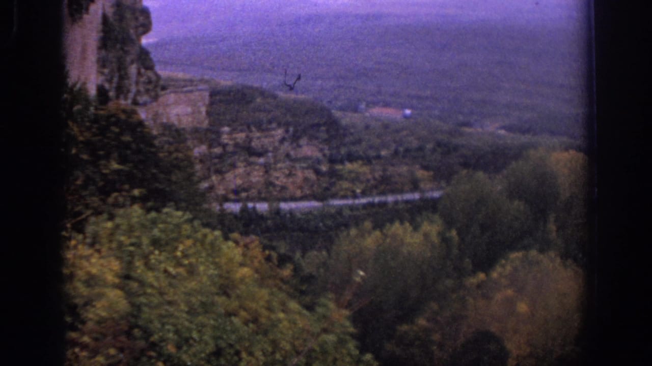 1966 Spain 8mm view from above trees toward a road and broad rural valley, with dark film borders visible.