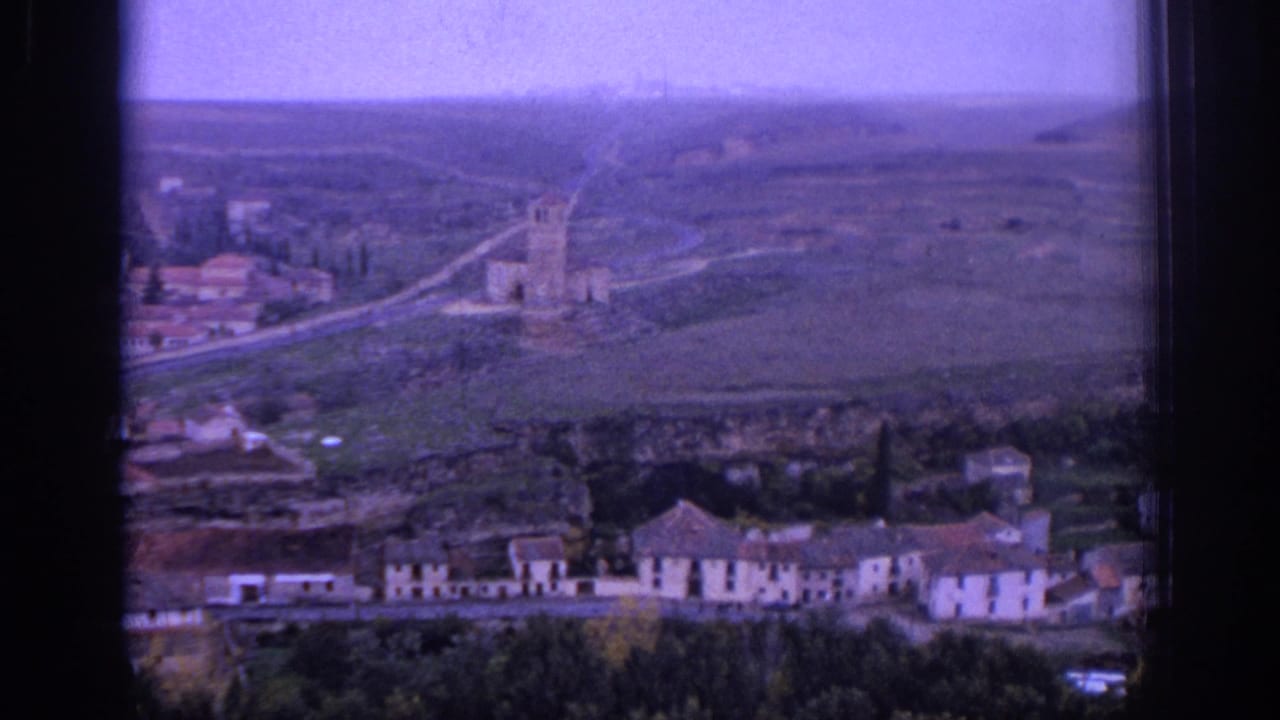 1966 Spain 8mm view of a distant village with a stone church tower, low buildings, roads, and open countryside.
