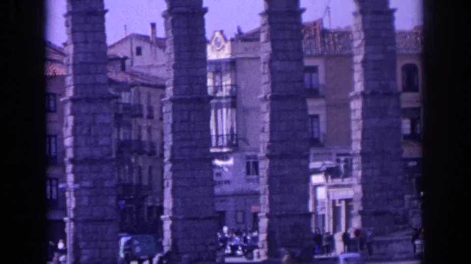 1966 Spain 8mm view of aqueduct piers over urban facades, with small pedestrians and vehicles visible below.