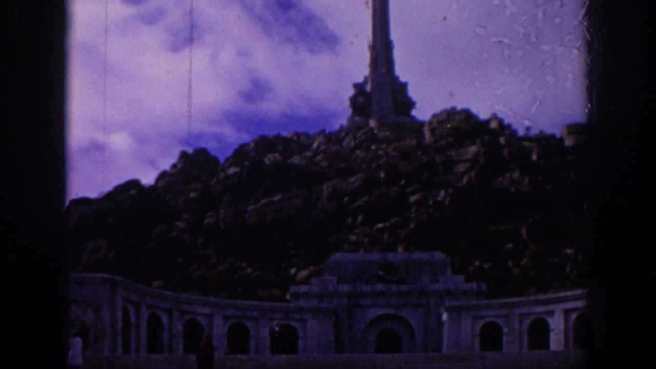 1966 Spain 8mm frame showing a monumental stone stairway and arched building set below a rocky peak and tall vertical structure.