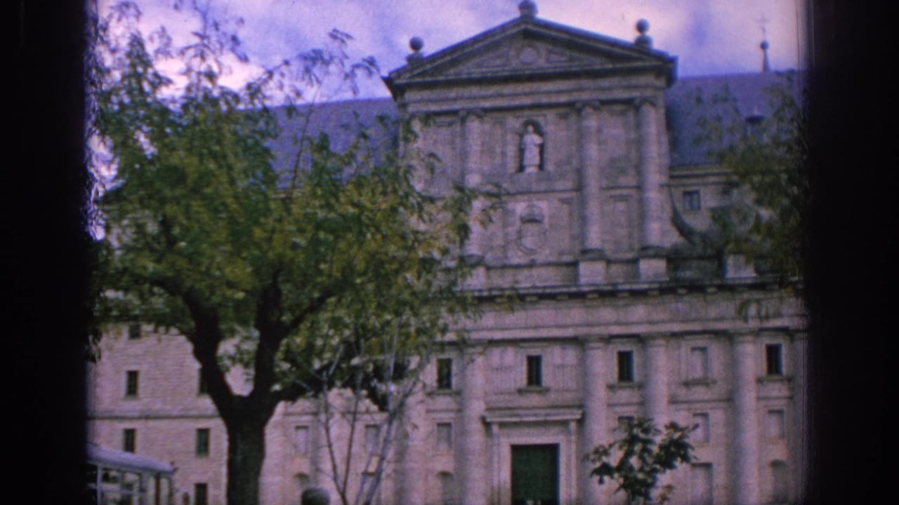 1966 Spain 8mm view of a historic stone facade with trees in the foreground and muted cloudy light.