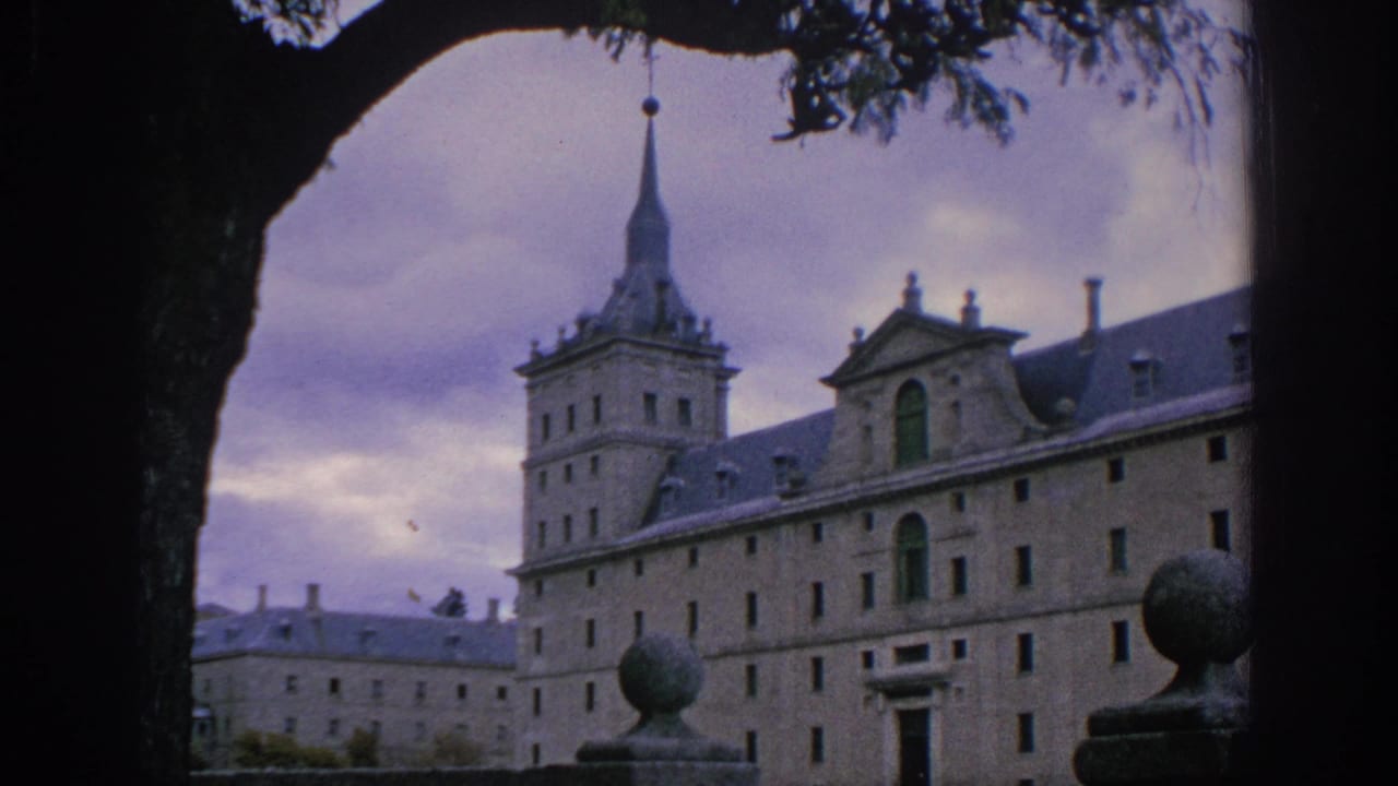 1966 Spain travel frame showing a long historic stone building, tower, spire, and balustrade ornament framed by a tree.