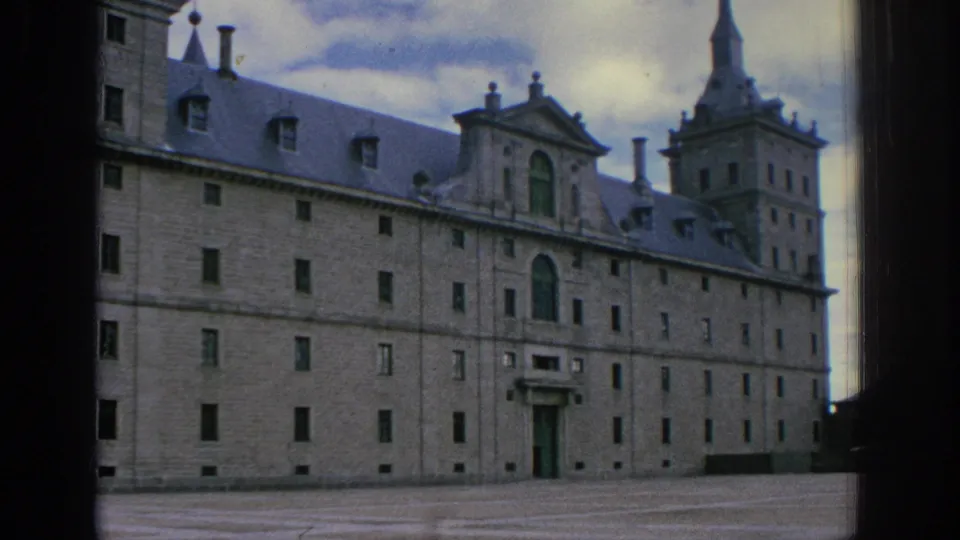 Wide 1966 Spain 8mm exterior of a historic stone museum or castle complex with tower, arched entry, and open forecourt.