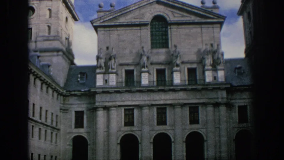1966 Spain 8mm frame showing a historic stone facade with roofline statues, columns, arched openings, and dark frame edges.